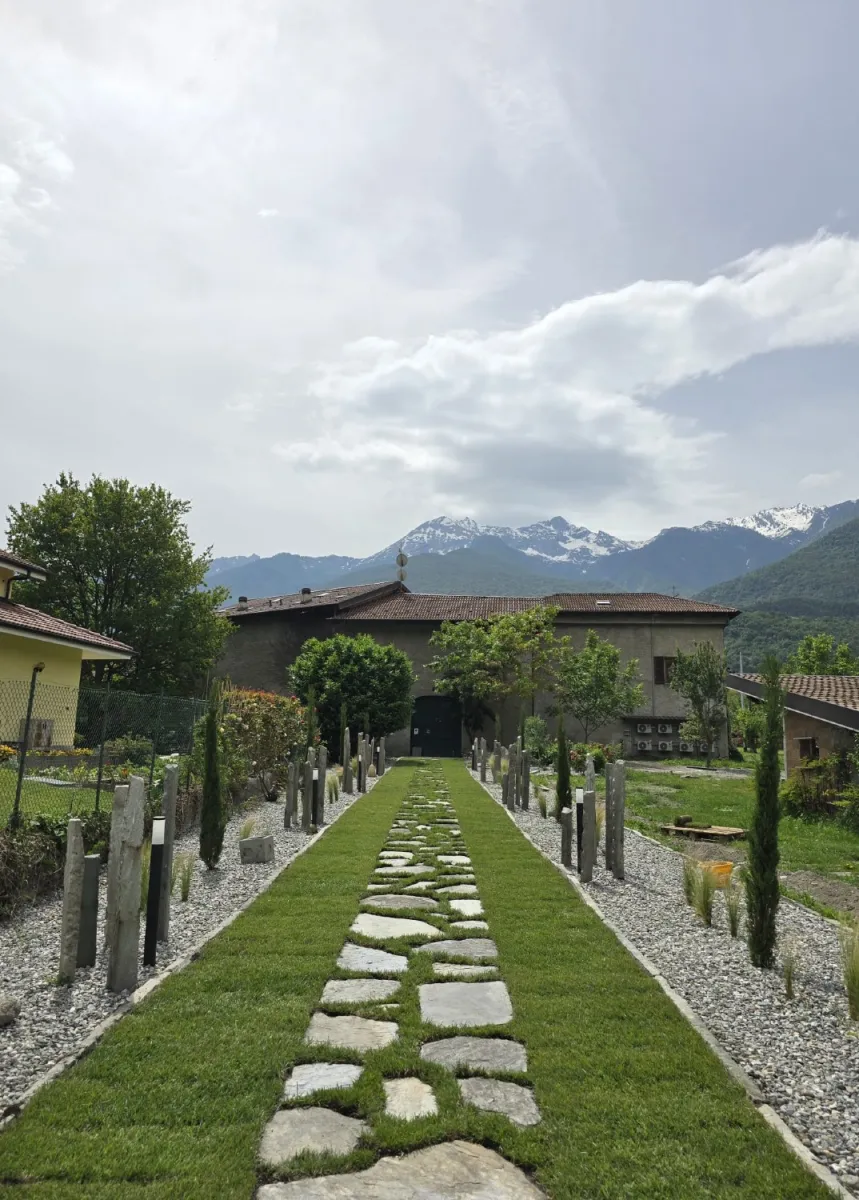 Viale d'ingresso con pavimentazione in prato e passi persi in lose e menir in pietra