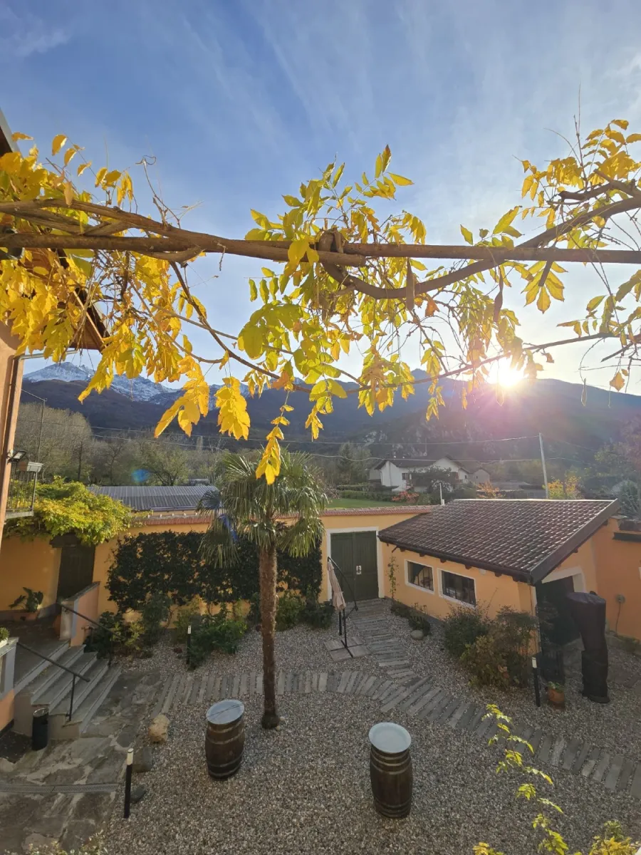 Cortile di una cascina con pavimentazione in ghiaia e passi persi in pietra